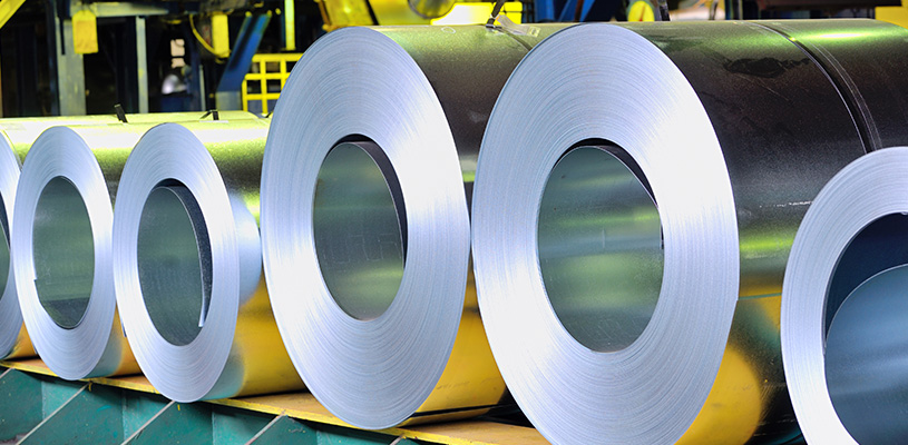 Multiple thin-gauge cold-rolled steel sheets being stored in roll form at a manufacturing plant.