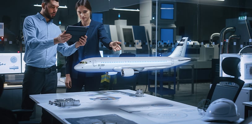 Two engineers using augmented reality to view a digital model of a commercial airplane in an office setting.